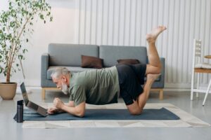 Older man stretching on a yoga mat at home – Spry Living low-impact fitness newsletter background