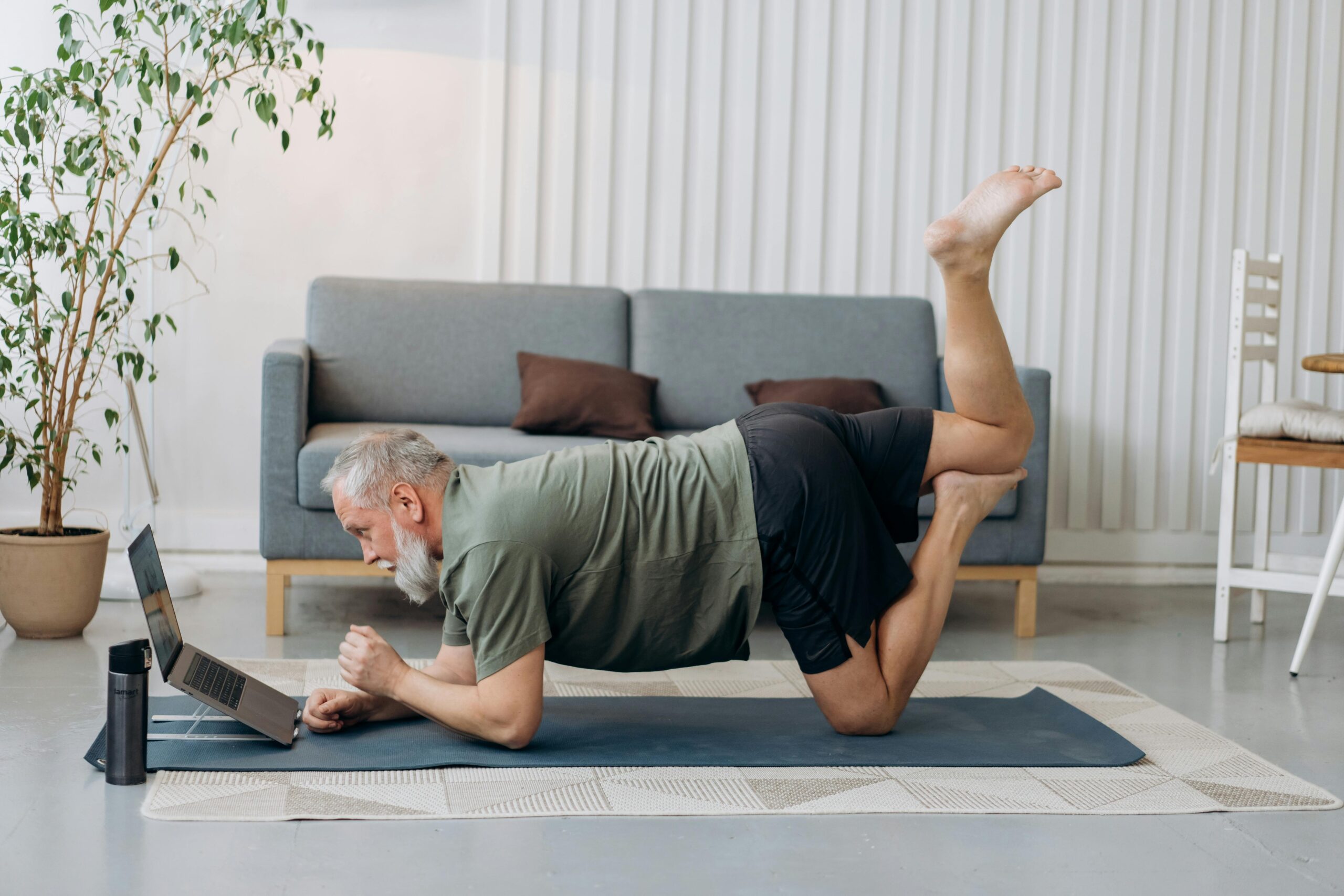 Older man stretching on a yoga mat at home – Spry Living low-impact fitness newsletter background